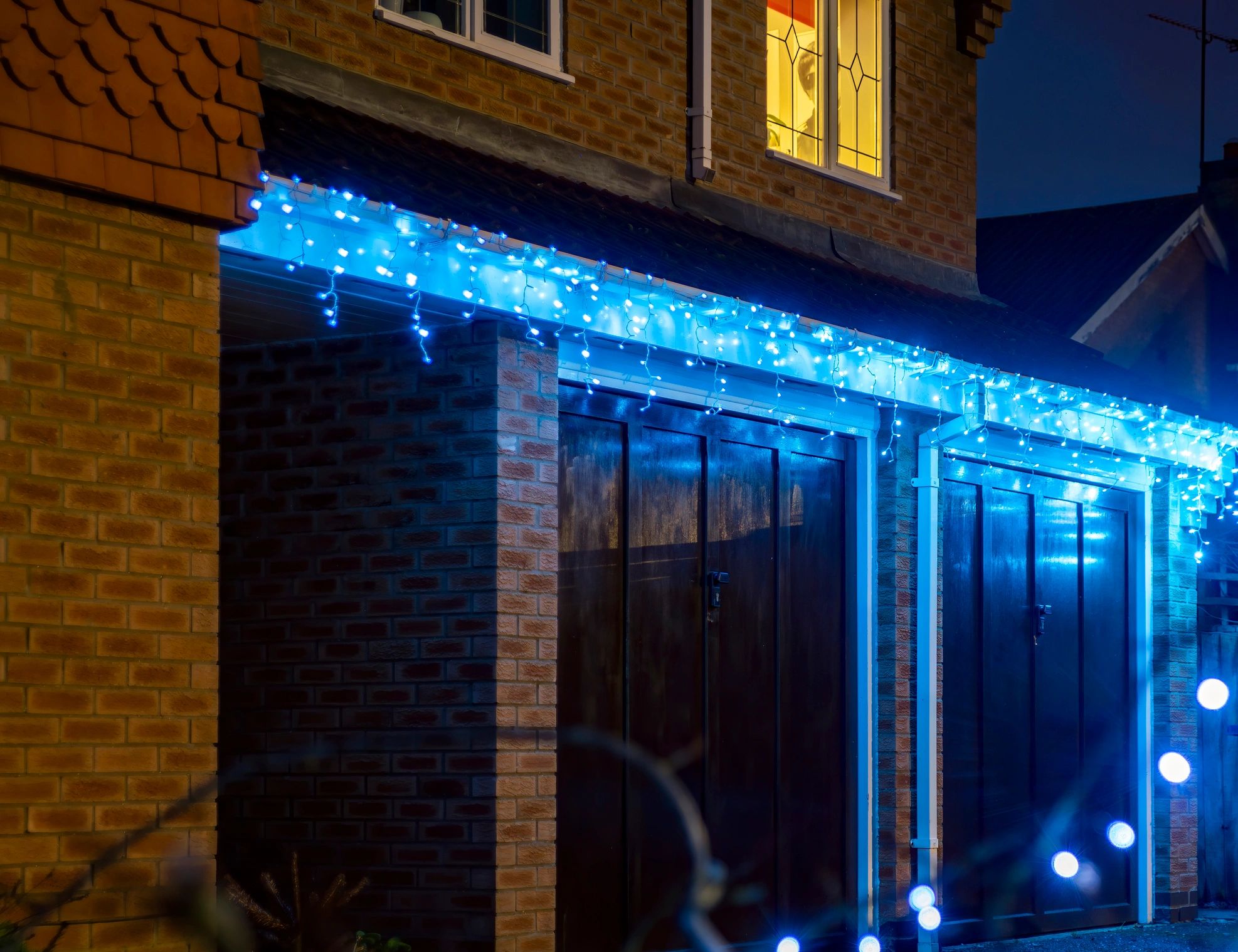 Home roofline decorated with Christmas lights at night
